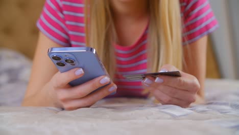 young woman paying with credit card online. home shopping with mobile phone. white female buying in web store with modern smartphone and internet connection. person making a purchase in mobile app