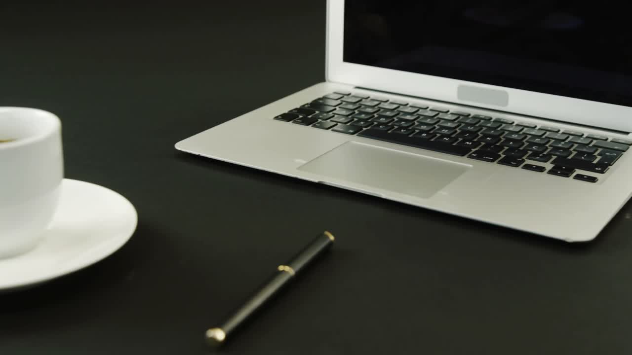 Laptop, coffee and pen on black background 4k