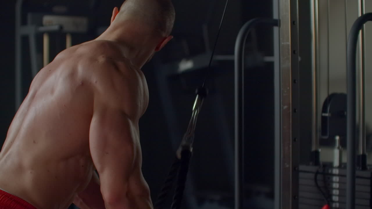 concepto de culturismo. hombre musculoso haciendo cuerda de cable tríceps tirar hacia abajo ejercicio mientras trabaja en el gimnasio
