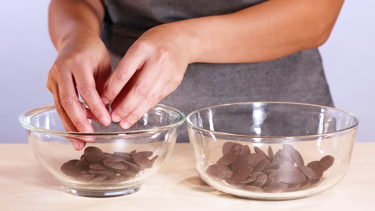 manos transfiriendo trozos de chocolate entre cuencos de vidrio