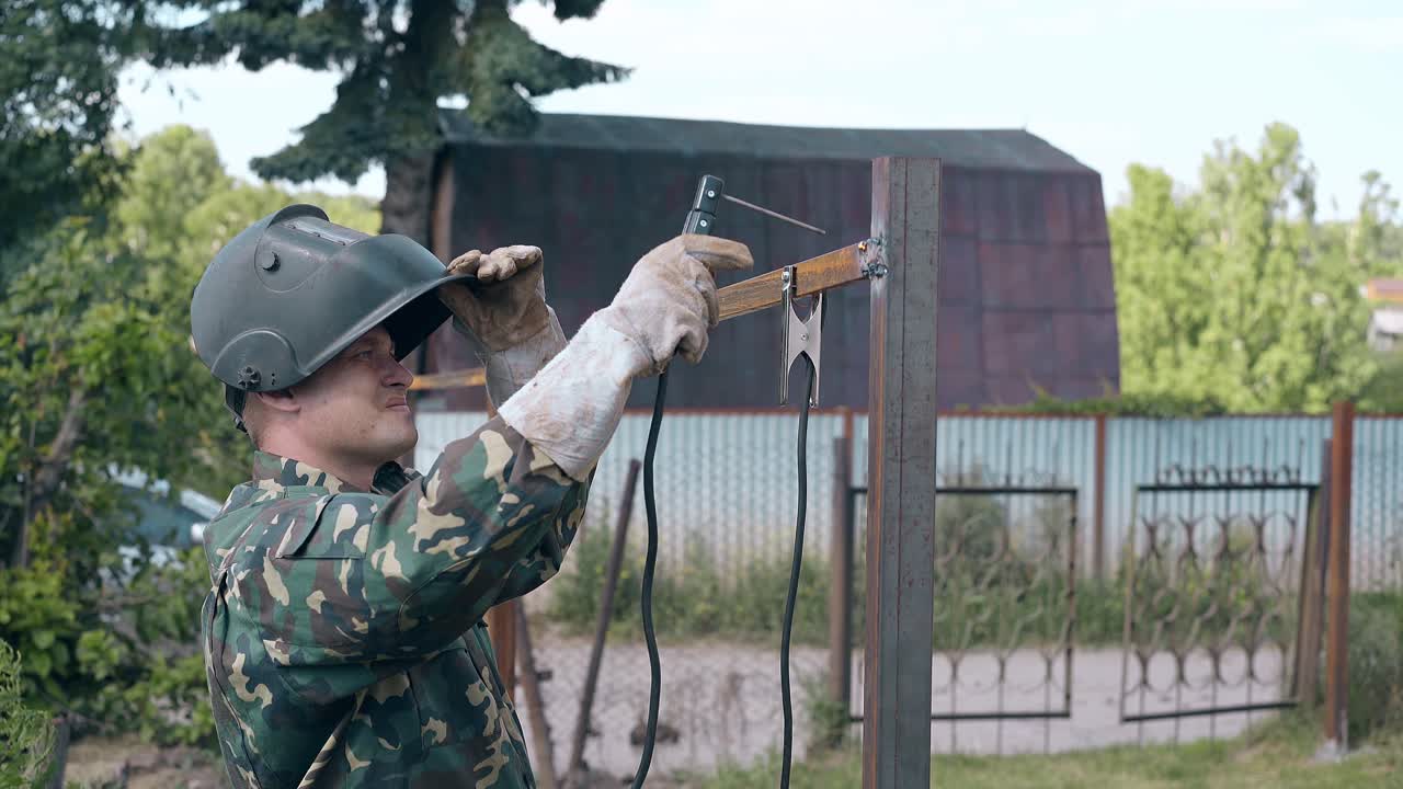 측면 보기 숙련 된 수리사 는 녹슬은 울타리 사체 를 용접 한다