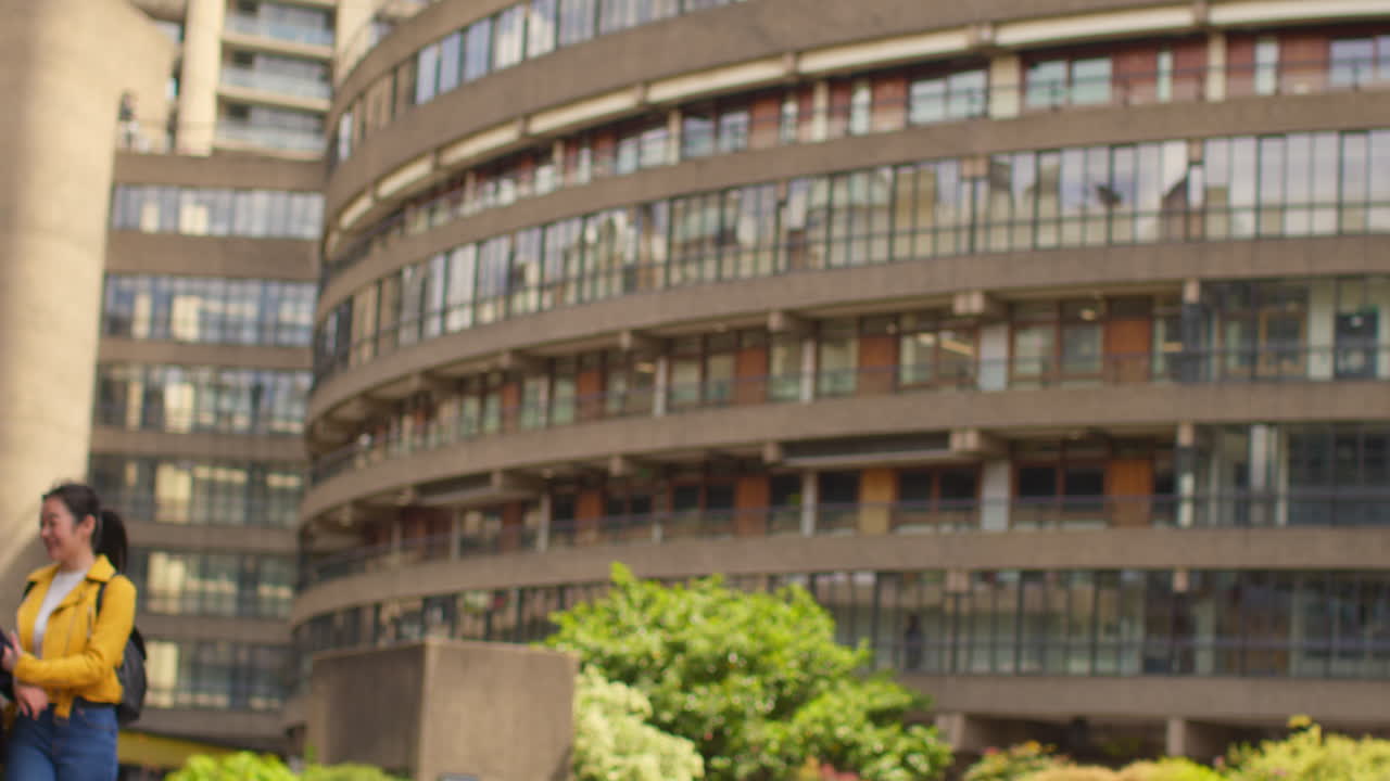 두 명의 미소 짓는 젊은 여성 친구들이 함께 도시 거리를 따라 야외에서 는 동안 대화하고 있습니다.