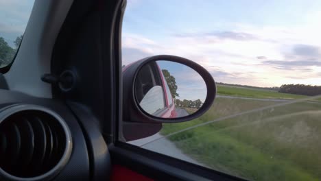 viajando en auto por la carretera al atardecer, a través de la vista trasera el camino va hacia atrás, hermoso paisaje en el fondo