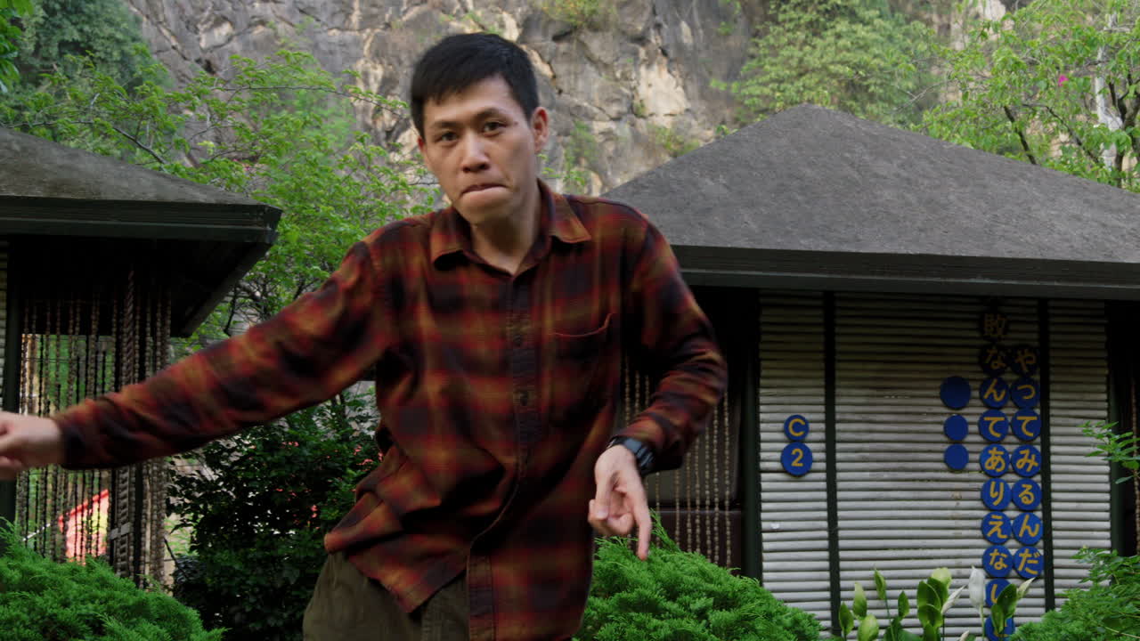 집중 된 숙련 된 아시아 젊은 남자가 야외에서 프리스타일 단계를 춤추고 있습니다.