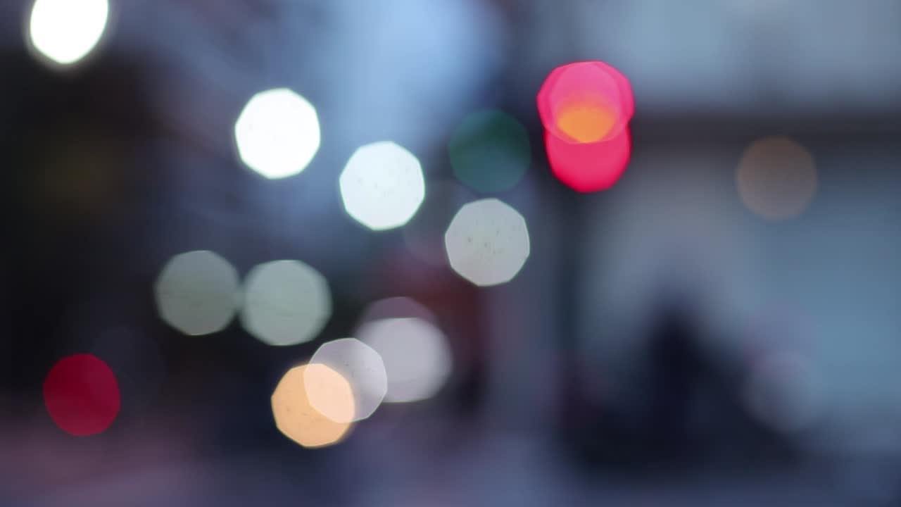 Blurry footage of street and traffic light with people crossing on the dark afternoon