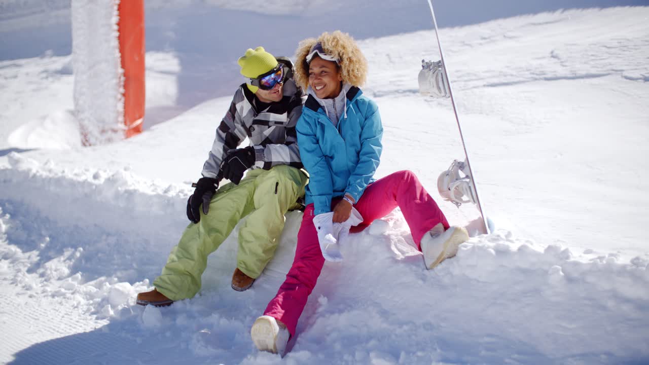 una pareja feliz relajándose en una plataforma de nieve.