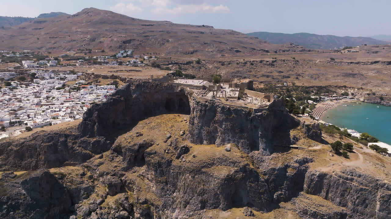 Drone rising around the Lindos hilltop fortress, sunny day in Rhodes, Greece