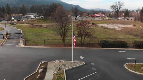 Aerial-shot-of-the-American-Flag-at-half-staff-with-field-and-mountain-in-background