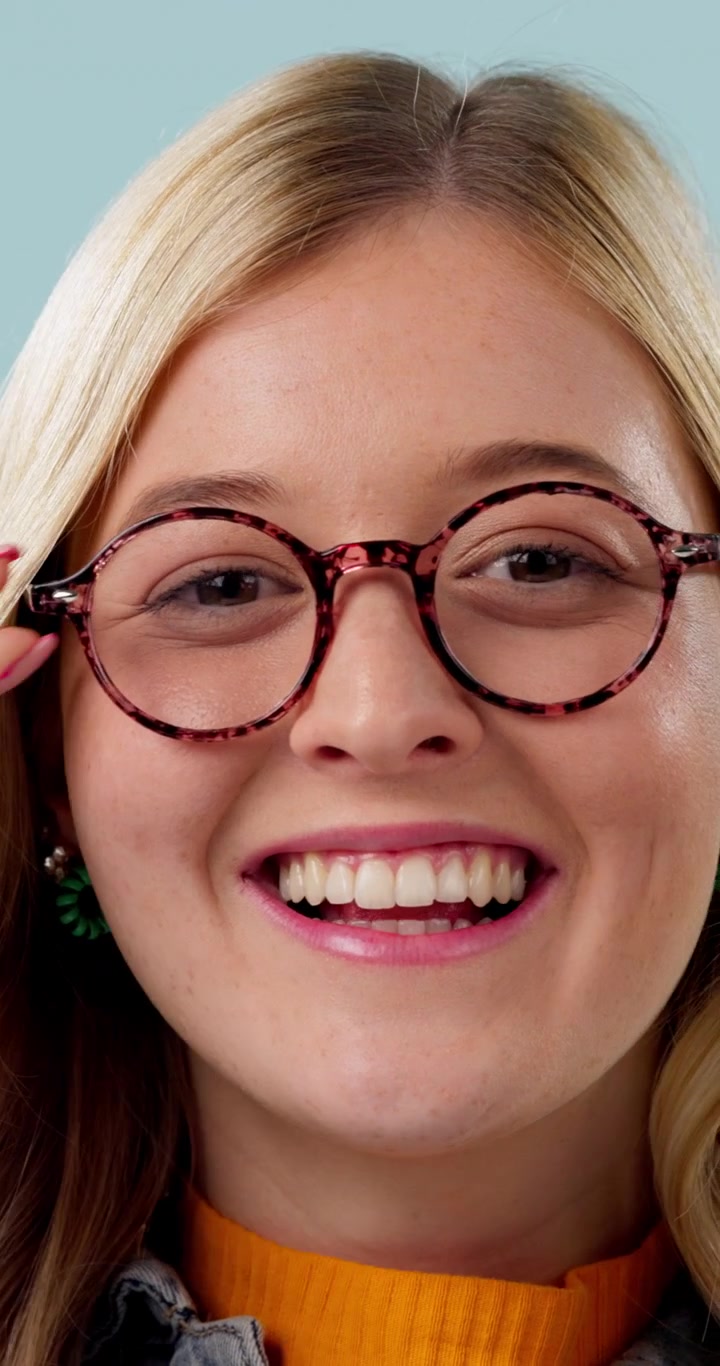 Young Woman Putting On Stylish Round Glasses and Smiling