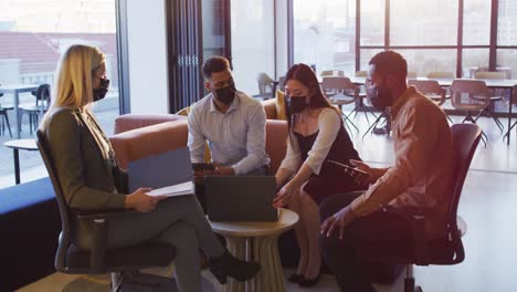 group of diverse businesspeople sitting at table discussing together and using laptop