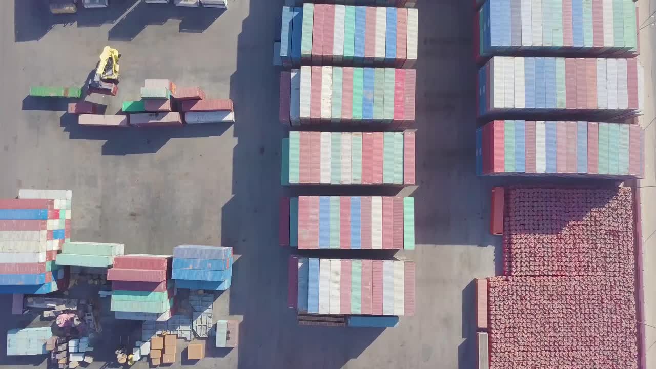 컨테이너 운반선이 컨테이너를 들어 올리고 트럭이 주차되어 있는 동안 컨테이너가 쌓인 넓은 마당