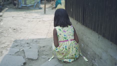 young indian poor orphan girl, stands up and walks on road with naked dirty feet in her rural village