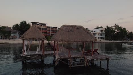 aerial view rotating around wooden deck in front of the beach in alea, tulum during sunset