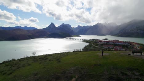 Aerial-reveal-of-family-in-a-swing-playing-with-their-child-at-the-viewpoint-in-Riaño,-a-village-in-León,-Spain-on-the-shore-of-a-large-reservoir-in-the-Cantabrian-mountains