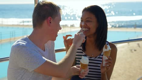 una joven pareja feliz tomando helado en la playa 4k