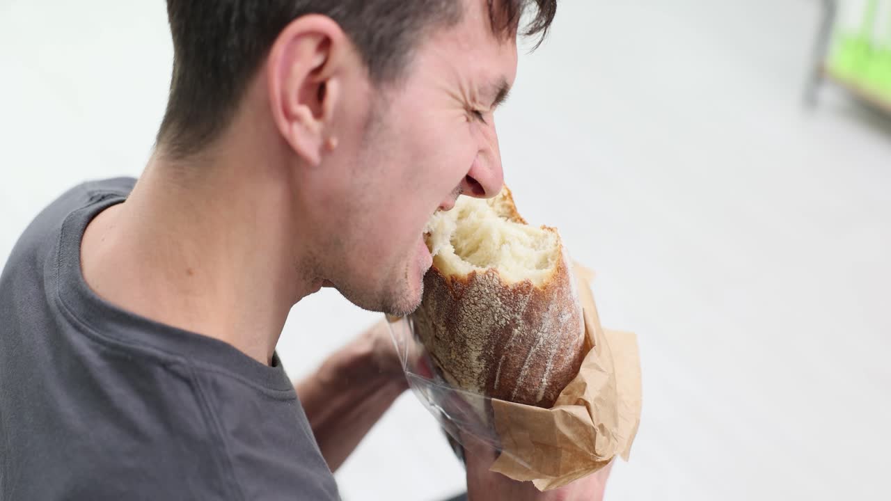 A man is eating a loaf of bread