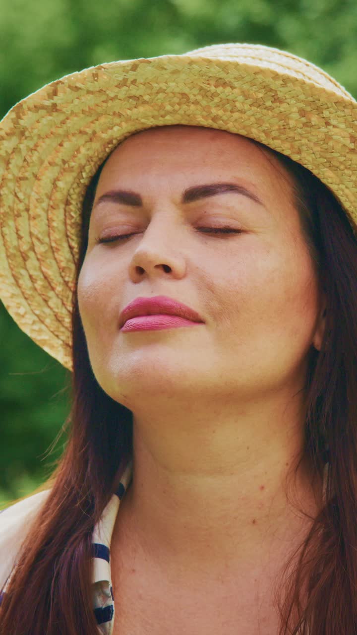 A Serene Woman in Nature: Embracing Peace and Tranquility with Eyes Closed Under the Warm Sun, Wearing a Stylish Straw Hat