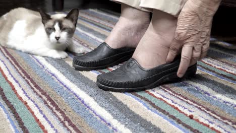 elderly woman swollen feet putting on shoes at home