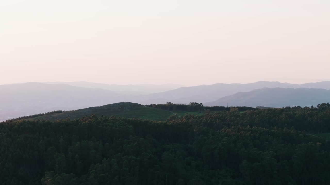 Layered mountain silhouettes fade into misty light over forested hills in the Minho region