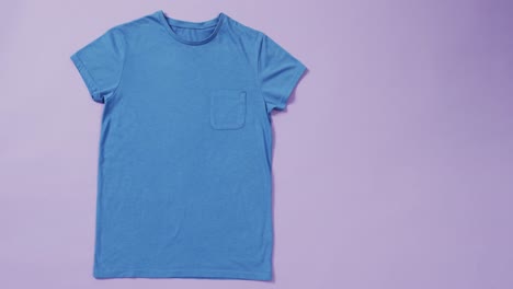 video of blue t shirt with tag and copy space on purple background