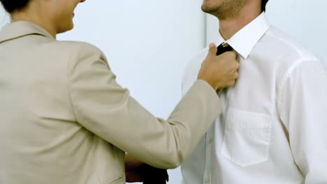 mujer de negocios ayudando a un hombre a atarse la corbata