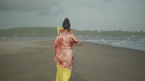 Niña-Feliz-En-La-Playa-Con-Una-Cometa-Voladora,-Cometa-Roja-Y-Amarilla-Y-Traje,-Mujer-Linda