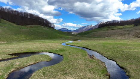 Vuelo-Sobre-Un-Sinuoso-Arroyo-De-Montaña-Con-Agua-Clara-En-Un-Soleado-Día-De-Primavera