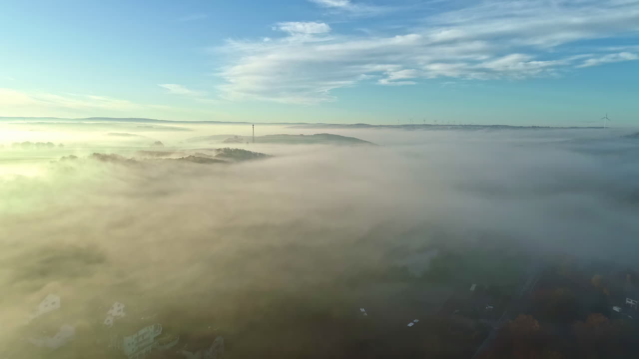 un dron aéreo disparó hacia adelante sobre un paisaje rural verde a través de nubes blancas en una mañana soleada
