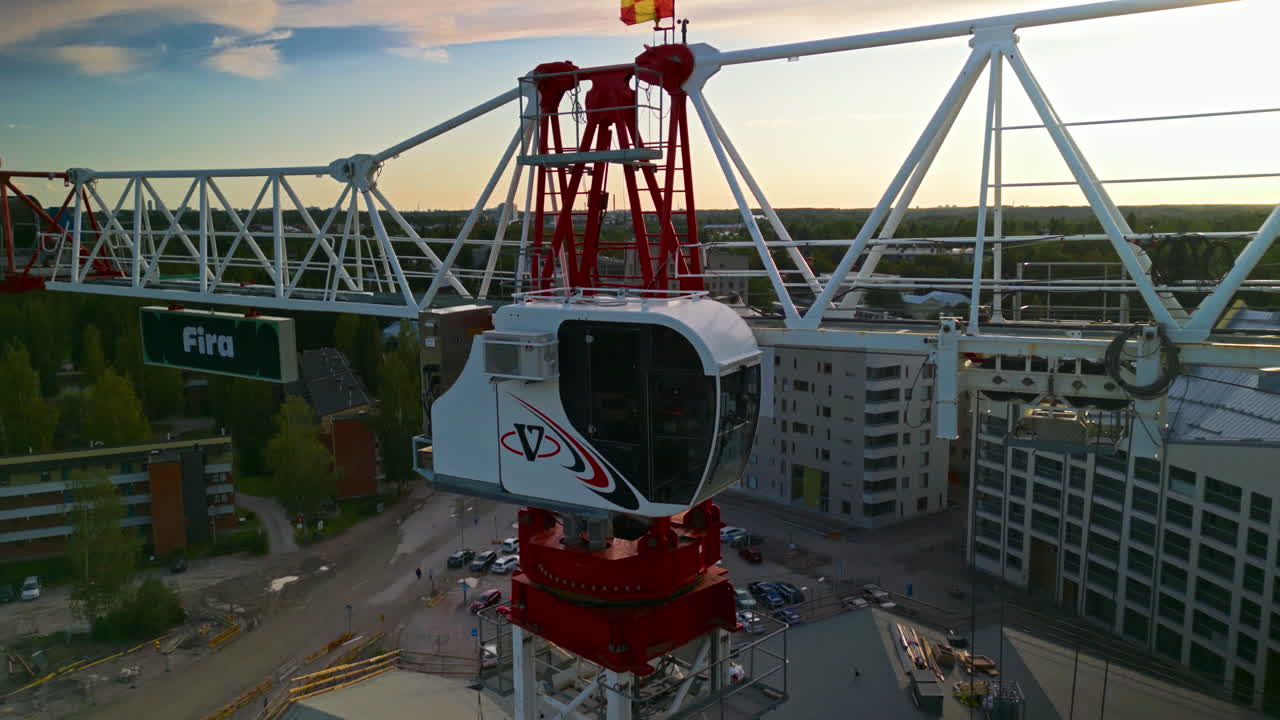 el gabinete de una grúa de construcción plana en el atardecer, el bosque y los edificios en el fondo