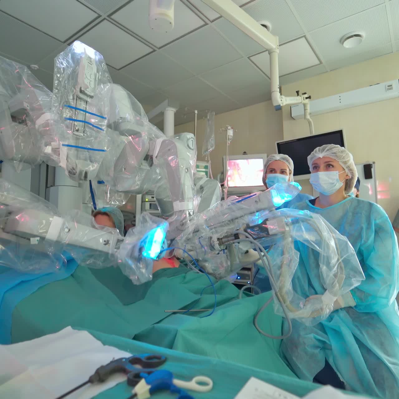 Robotic machine with moving arms during minimally invasive surgery. Future surgical innovation in the operating room. Team of doctors observe robotic surgery