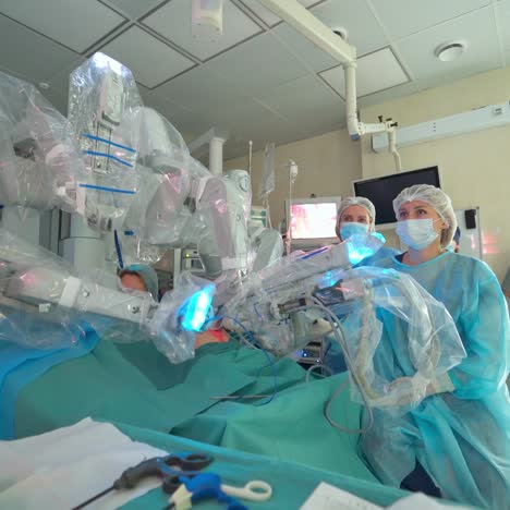 robotic machine with moving arms during minimally invasive surgery. future surgical innovation in the operating room. team of doctors observe robotic surgery