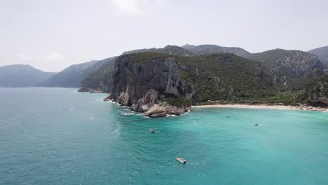 Boats-On-Mediterranean-Sea-Backdropped-By-Cala-Luna-Beach-In-Sardinia,-Italy