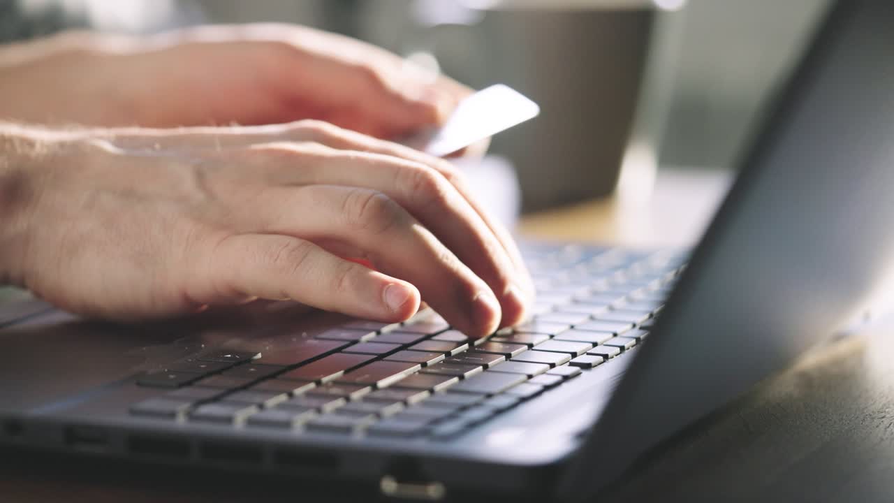 primer plano. un hombre paga por compras en una tienda en línea usando una tarjeta de crédito y una computadora portátil