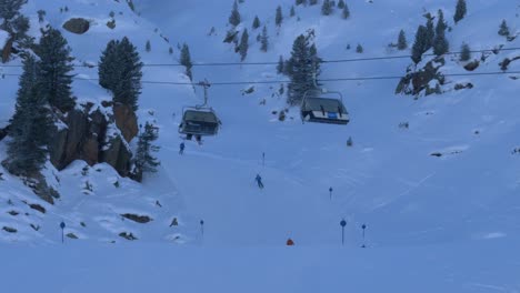 ski lifts moving up and down while skiers ride downhill on the slopes of kaunertal, austria - static view