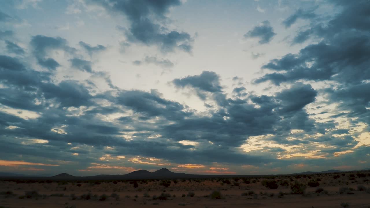 nubes de tormenta pasando sobre el desierto de mojave al amanecer naranja y azul, lapso de tiempo