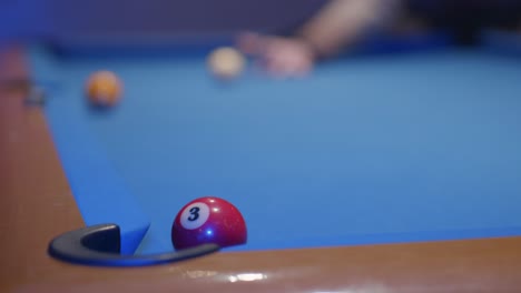 man practices snooker and puts two balls in the holes with one shot