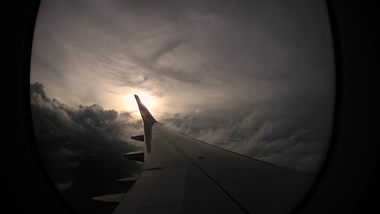 Solnedgang og smukke skyer set fra flyvinduet i venstre side vækker rejselysten.