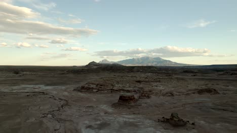 a distant mountain beyond a rugged desert terrain - aerial flyover