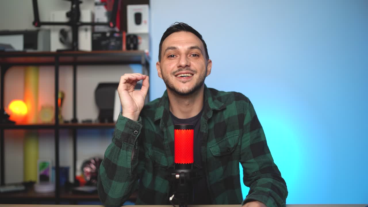 A social media content creator records his podcast using a pro microphone and DSLR camera in a modern podcasting setup.