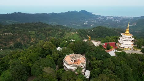 Truck-shot-with-unique-view-of-a-Koh-Samui-hill-temple-on-a-green-mountain,-ocean-in-the-background,-slow-motion