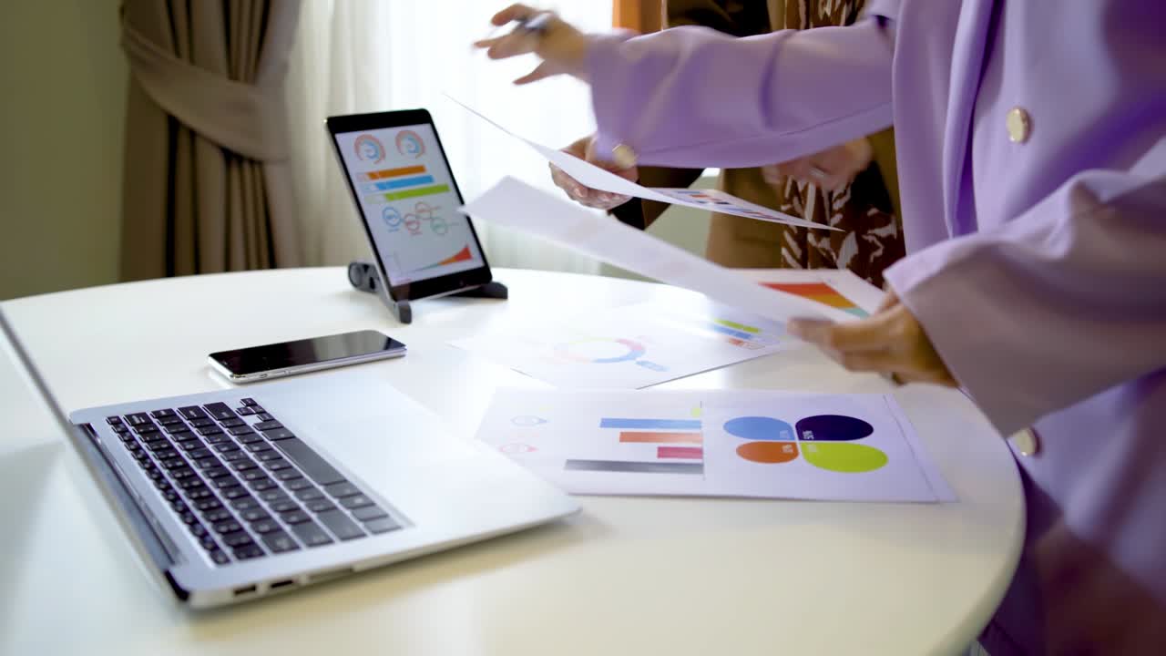 dos mujeres de negocios musulmanas contadoras apuntando papel mostrando gráfico gráfico en el trabajo en la oficina analizando las hojas de datos, computadoras portátiles, tabletas y gráficos en sus escritorios