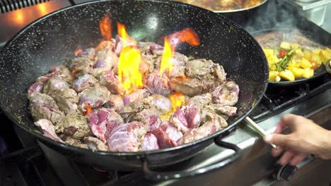 Close-up-of-person-cooking-a-delicious-stew-in-the-pan-while-a-flame-is-coming-out