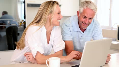una pareja feliz tomando café juntos y usando una computadora portátil