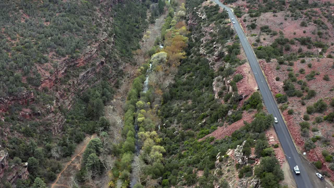Aerial ascending pull back reveal above Sedona road Arizona vehicles driving long wilderness highway road