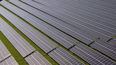 Tele-Lens-Slide-over-a-huge-solar-power-plant-with-multiple-solar-panels-on-a-green-hill-in-Germany,-Renewable-Energy,-Aerial-Footage