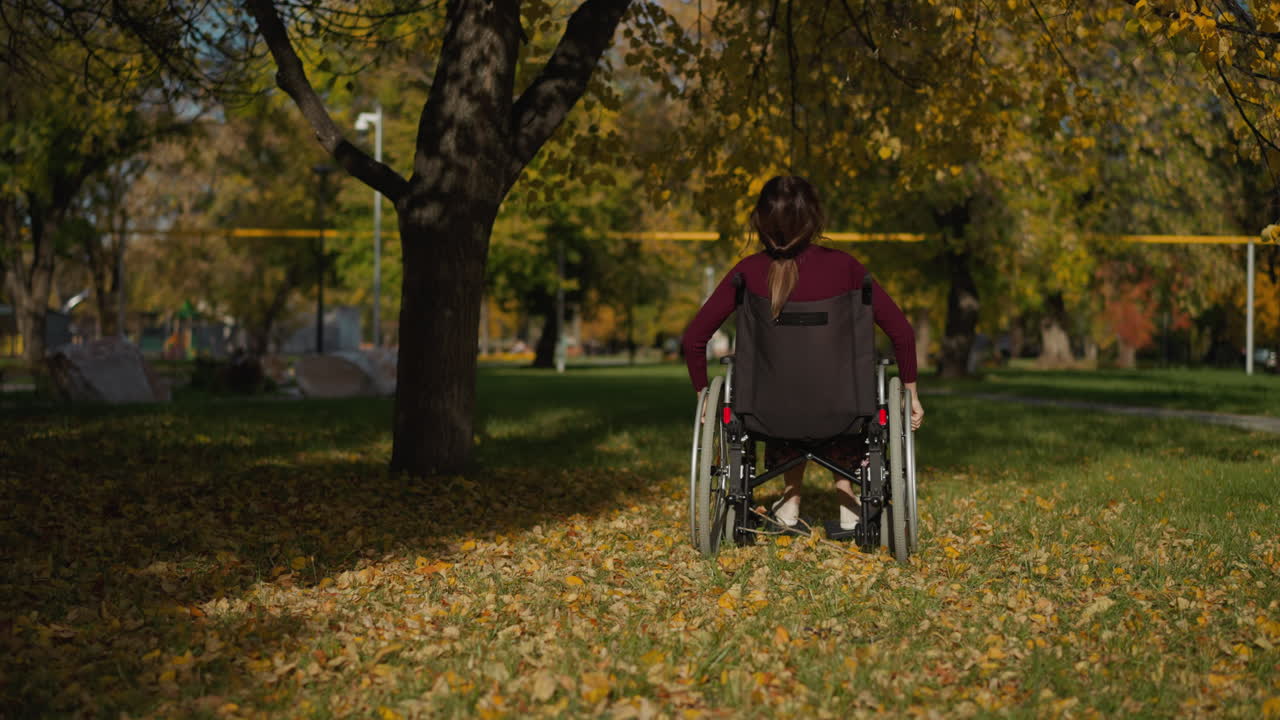 어린 여성은 나무 아래  ⁇ 체어에 앉아 공원에서 휴식을 취합니다.