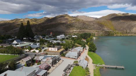 drone view of township of cromwell under clouds with beautiful landscape of mountains at background in new zealand