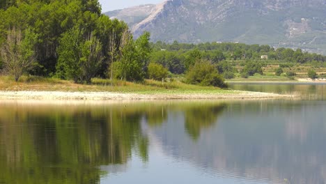 Lago-Tranquilo-Que-Refleja-árboles-Y-Montañas-En-La-Superficie-Del-Agua,-Cámara-Lenta