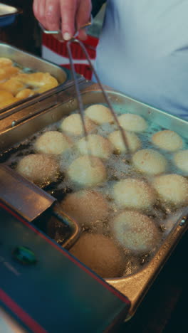 frying dough balls in oil, street food vendor preparing delicious snack in wuzhen, china