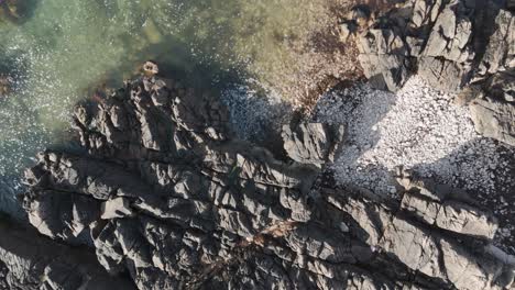 Niedrige-Drohnenaufnahmen-Des-Kristallklaren-Meeres-über-Granitfelsen-Mit-Plätschernden-Wellen,-Felsbecken-Und-Buchten-An-Einem-Sonnigen-Tag